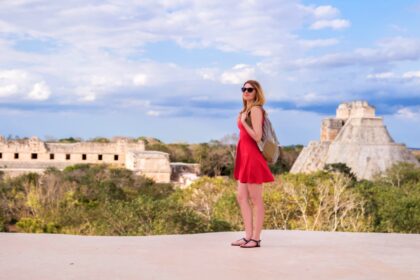 solo female traveler looks out at uxmal maya ruins in mexico