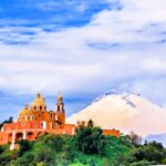 cholula cathedral Puebla with the popocatepetl volcano, exuding smoke in the background