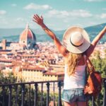 woman with arms outstretched looking at florence city skyline in tuscany italy
