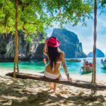 Happy traveler woman in bikini relaxing on swing under tree looking destinations sea beach, Lao Lading island, Andaman sea, Krabi, Phuket, Travel Thailand, Tourist Asia, Summer holiday vacation trip