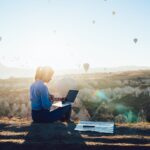 Woman working on laptop and watching hot air baloons in Turkiye