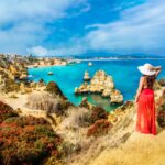 Woman in a red dress looking at the sea in the Algarve, Portugal