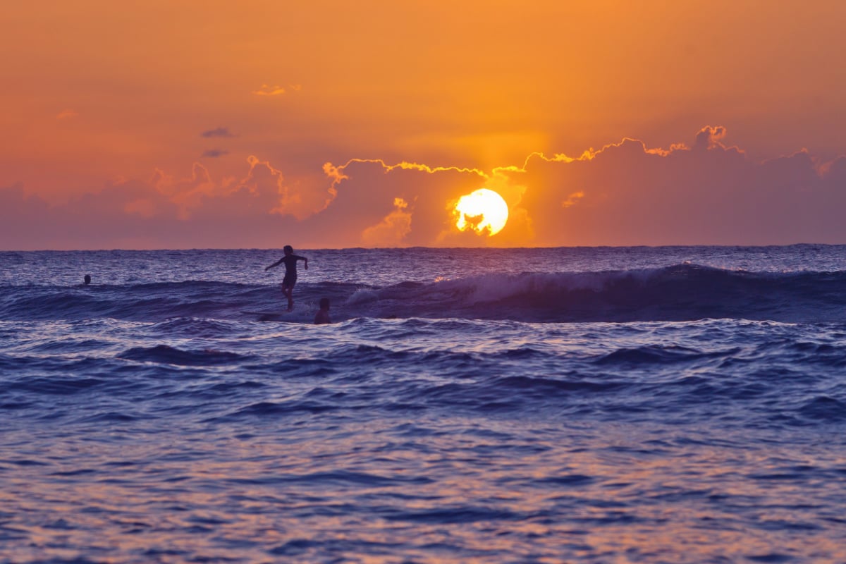 A young surfer is silhouetted against the setting sun at Domes Beach. Rincon is a popular surfing destination for tourists in the winter months.