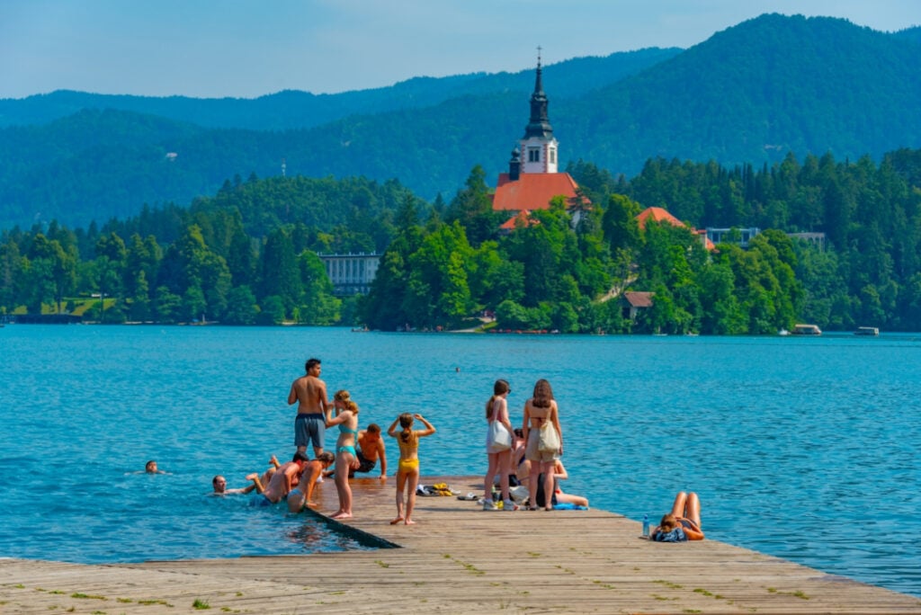 People swimming in front of the Assumption of Maria church at Lake Bled in Slovenia