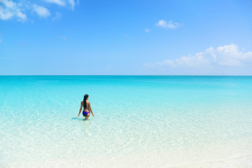 Woman entering the ocean in crystal clear blue water of South Caicos