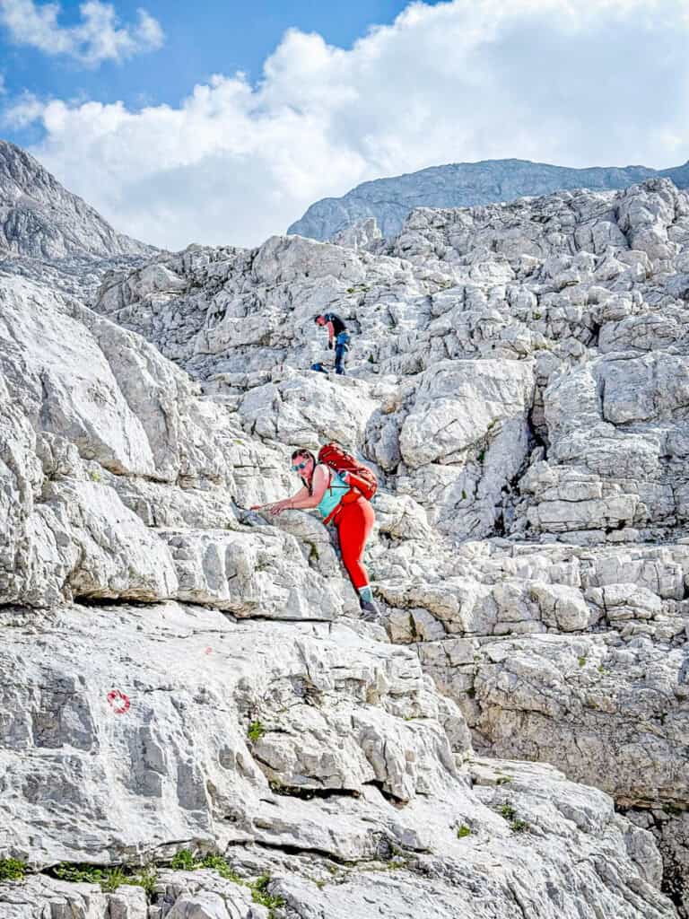 woman holding off edge of cliff while scaling arount it mt triglav